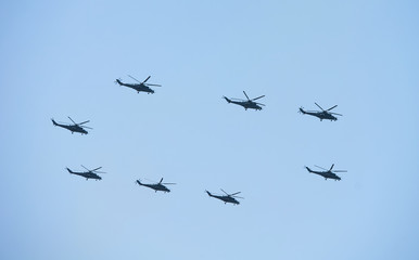 Military helicopters maneuvers in the blue sky. Group combat helicopters in flight during a military demonstration