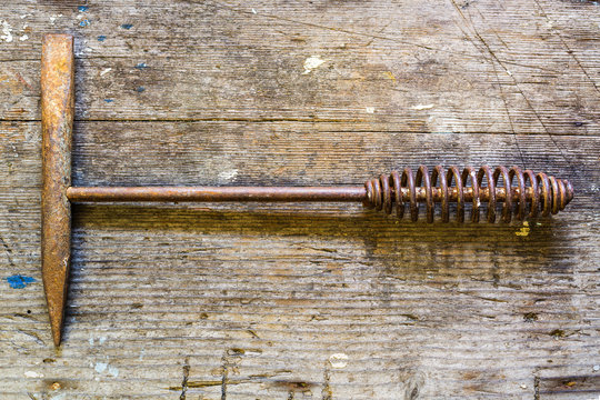 Close up of an old rusty welder's chipping hammer on a weathered wood background