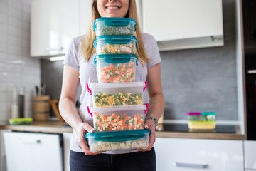 Woman holding containers with frozen mixed vegetables.