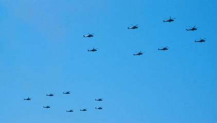 Military helicopters maneuvers in the blue sky. Group combat helicopters in flight during a military demonstration