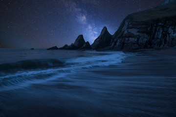 Vibrant Milky Way composite image over landscape of long exposure seascape of rocky coastline