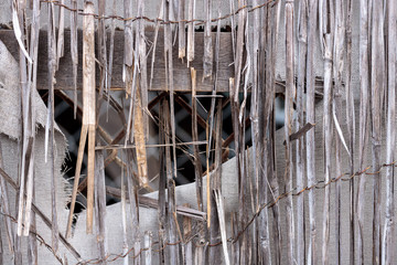 Vintage bamboo rattan close-up of a dilapidated retro worn fence, white fabric canvas with hole and frayed edges, chain link in background texture