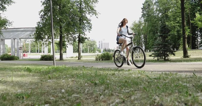 A young woman is cycling in the park.