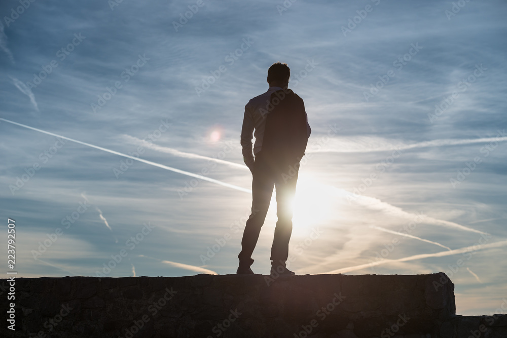 Wall mural man silhouetted against the setting sun