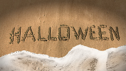Halloween background. Text inscription  Halloween on sea sand with waves