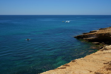 Sea cleared with kaiak on the left side and two motor boats approaching towards you and sailboat in the distance at the top.
