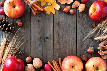 Autumn frame of apples and fall ingredients on a rustic wood background with copy space