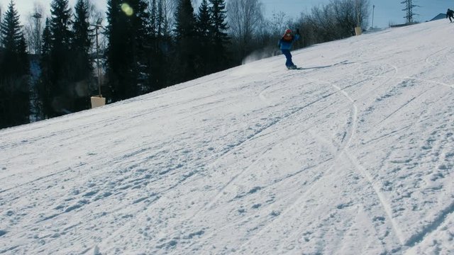 Teenage boy of 12 years in blue suit sliding on a snowboard from snow descent next sky lift and falls.