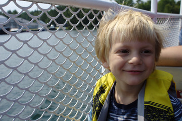 Cute Young Blond School Aged Boy Smiling on a Boat on the Lake in the Summer