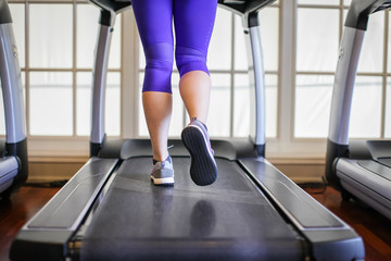 Fototapeta na wymiar woman legs in sneakers running on treadmill in gym. Health and sport concept background, Healthy lifestyles