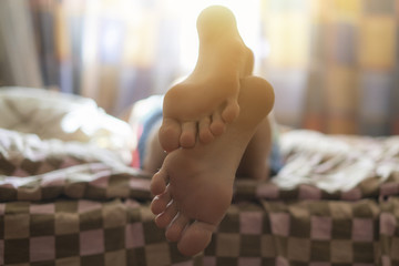 child sleep lying on the bed, close up bare foot in the morning at home f