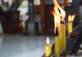 Yellow Candlesticks lit on the prayer shelf in Buddhist Temple Shrine. Buddhism, Asian traditional religious ceremony, Rituals, Making a wish, Meditation, Praying, Offering concept