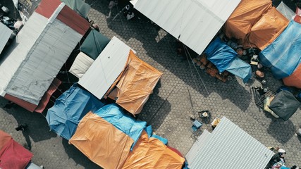aerial drone image of the morning city market with colorful tents looking down