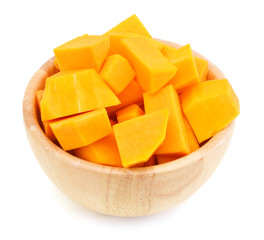 A group of cut and slice butternut squash chunks in wooden bowl on a white background.