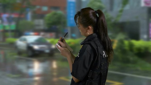Asian American Woman Police Officer at Crime Scene Taking Notes