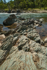 Massive green granite rock formations leading into the flowing stream