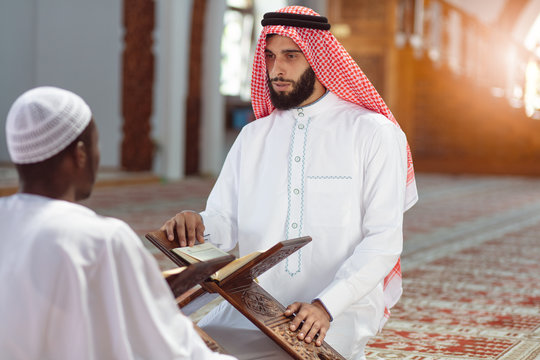 Muslim men praying with holy books in mosque
