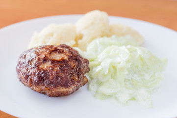 Polish kotlet mielony (meatballs) with mizeria and mashed potatoes.