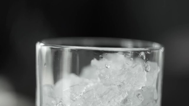Macro shot of ice crush falling into a cocktail glass. Making of cocktail.