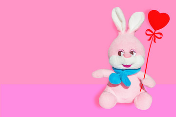 Obraz na płótnie Canvas Soft toy pink Bunny with blue scarf isolated with heart 
