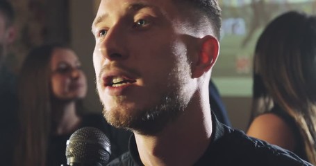 Man sings karaoke in a bar at night.