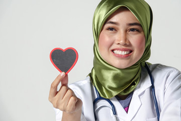 Smiling female doctor holding heart shape  studio portrait isolated on white background