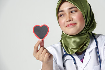 Smiling female doctor holding heart shape  studio portrait isolated on white background