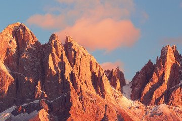 Fototapeta premium Beautiful mountain peaks covered by colored clouds at sunset, mountain landscape background