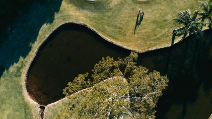 aerial image of a golf field course with a flag and hole and some sand and water pools with...
