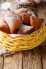 Tasty African Mandazi with powdered sugar close-up in a basket. vertical