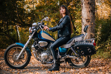 Obraz na płótnie Canvas Girl on a motorcycle in a black jacket and leather pants. Women biker