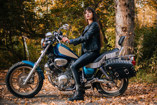 Girl on a motorcycle in a black jacket and leather pants. Women biker