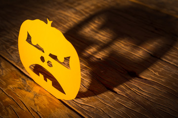 Halloween background concept. Jack O pumpkin angry face, graphic shadow and hard light on wooden table