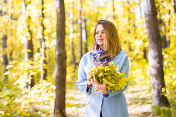 Fall, season, people concept - woman with yellow autumn leaves