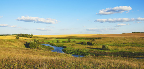 Beautiful view of river curve,green and yellow fields illuminated by the warm light of setting sun.
