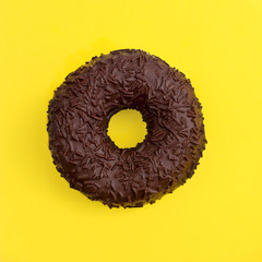 Chocolate donut on a yellow background top view in a square