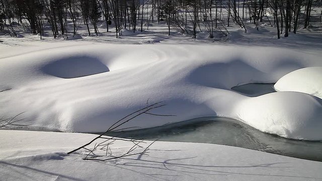 winter landscape snow drifts on a mountain river close-up.  freezing stream of ice on the edges of the shore. A warm Sunny evening light and shadows on the snow