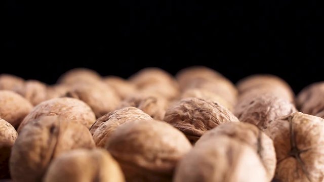 Close up of walnuts rotating on black surface background.