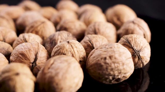 Close up of walnuts rotating on black surface background.