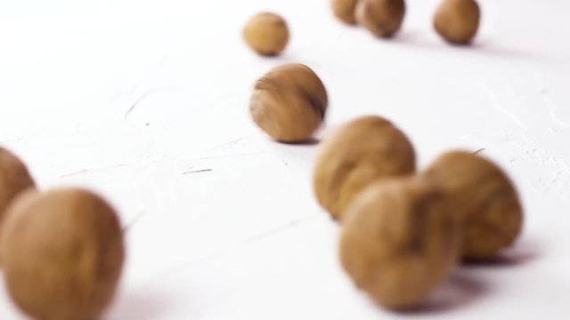 Many walnuts rolling on white textured surface. Close up.