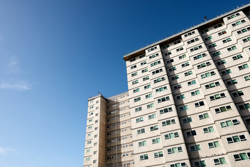 Social housing apartment tower block against a blue sky. 