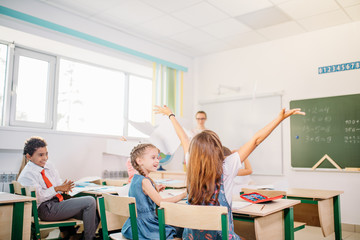 Kids having fun in school yard and throwing paper. holidays, weekends concept
