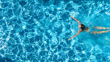 Foto auf Acrylglas Luftdrohnenansicht eines aktiven Mädchens im Schwimmbad von oben, junge Frau schwimmt im blauen Wasser, tropischer Urlaub, Urlaub im Resort-Konzept © Iuliia Sokolovska