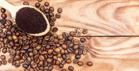 Wooden spoon with ground coffee and coffee beans on the table. Top view.