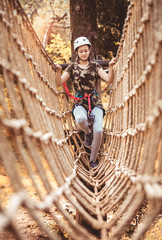 Obraz na płótnie Canvas Happy school girl enjoying activity in a climbing adventure park on a summer day