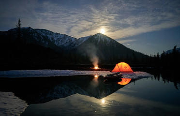 Orange tent on coast of lake at night.