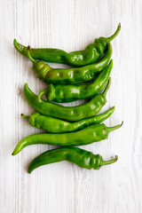 Green chili peppers on white wooden surface, top view. Flat lay, from above, overhead. Close-up.