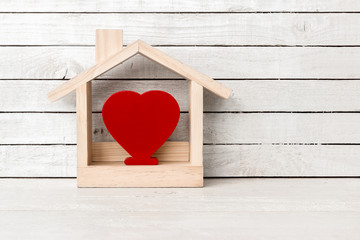 Wood Home Shaped with red heart shaped on white wood over white wood background.