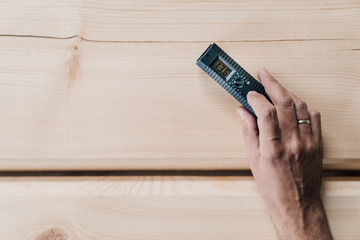 a device for measuring the humidity of wood in a hand on a wooden beam