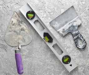 Building tools on a gray concrete background. Spatula, trowel, level, level, top view.